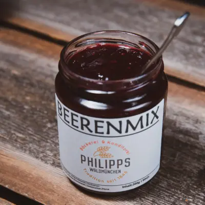 Ein Glas Beerenmix von Philipps mit einem Löffel auf einem Holztisch.