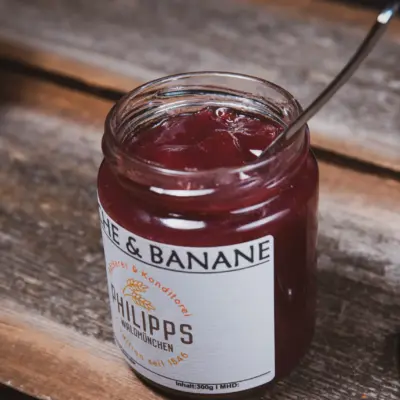 Glas mit Kirsch-Bananen-Aufstrich von Philipps auf einem Holztisch.