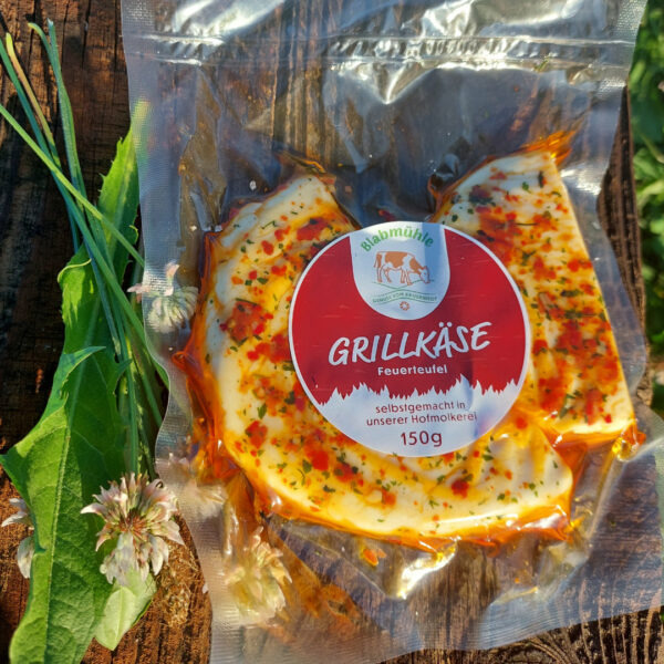Grillkäse Feuerteufel vakuumverpackt auf Holzbrett und Löwenzahn
