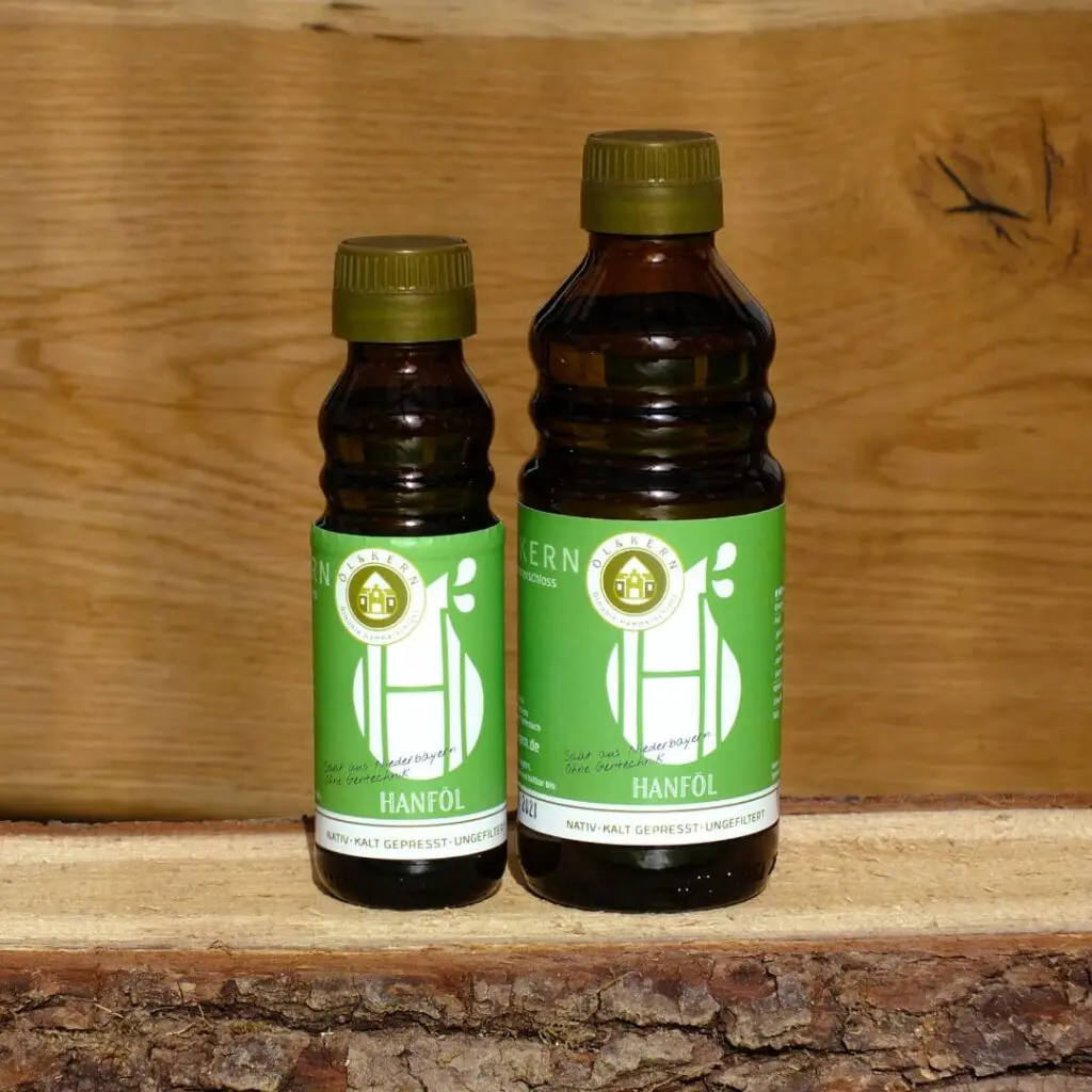 Hanföl klein und groß in Glasflasche auf Holzbrett