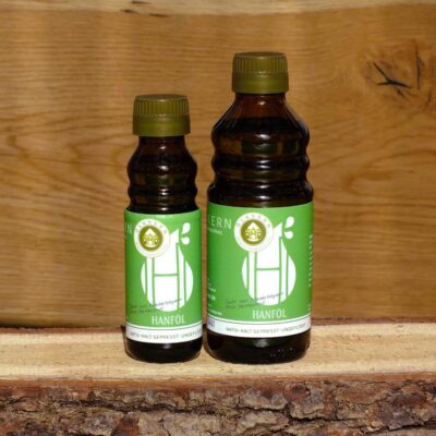Hanföl klein und groß in Glasflasche auf Holzbrett