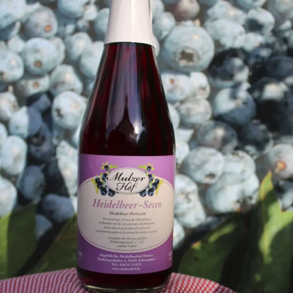 Heidelbeersecco in der Flasche auf frischen Heidelbeeren