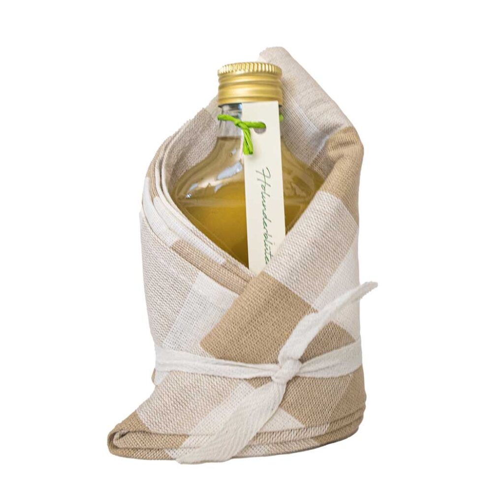 Rosenblütensirup in Glasflasche im Geschirrtuch