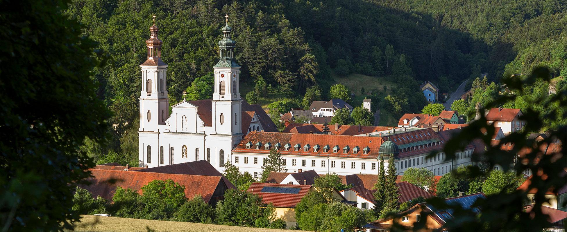 Großes Kloster mit zwei Türmen und viel Wald im Hintergrund