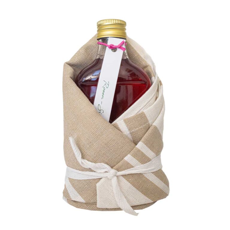 Rosenblütensirup in Glasflasche im Geschirrtuch