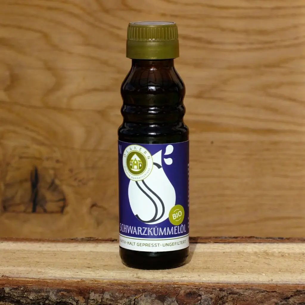 Schwarzkümmelöl in Glasflasche auf Holzbrett