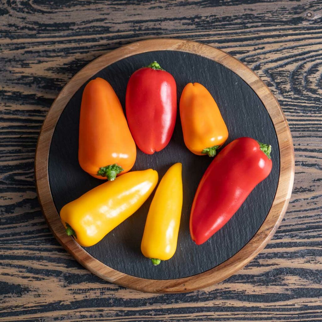 Snackpaprika auf schwarzem rundem Holzbrett