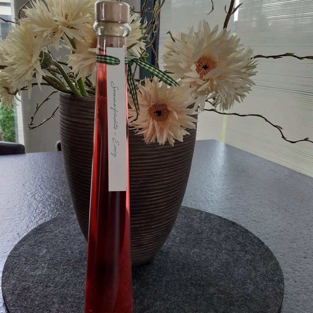 Sommeressig in Glasflasche auf Blütendeko