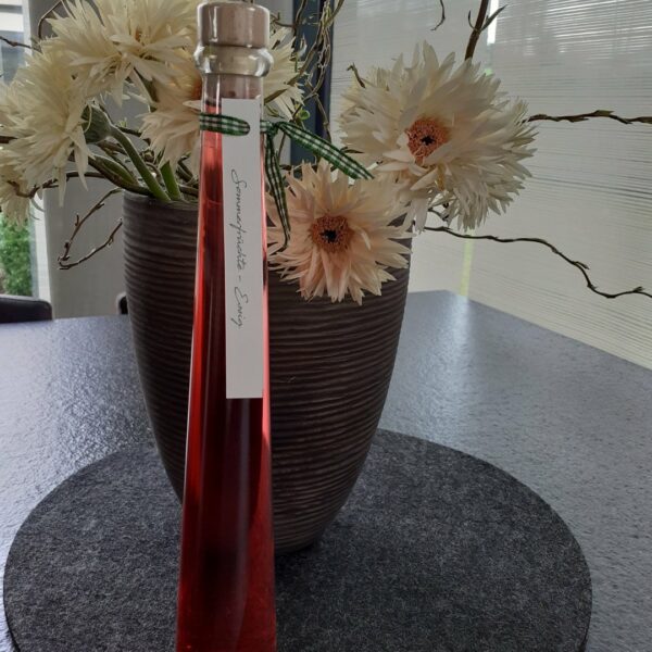 Sommeressig in Glasflasche auf Blütendeko