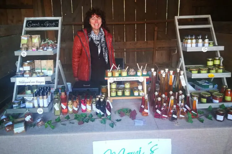 Ein Marktstand mit einer Vielzahl von Lebensmitteln, darunter Marmeladen und Säfte, auf einem Tisch präsentiert.