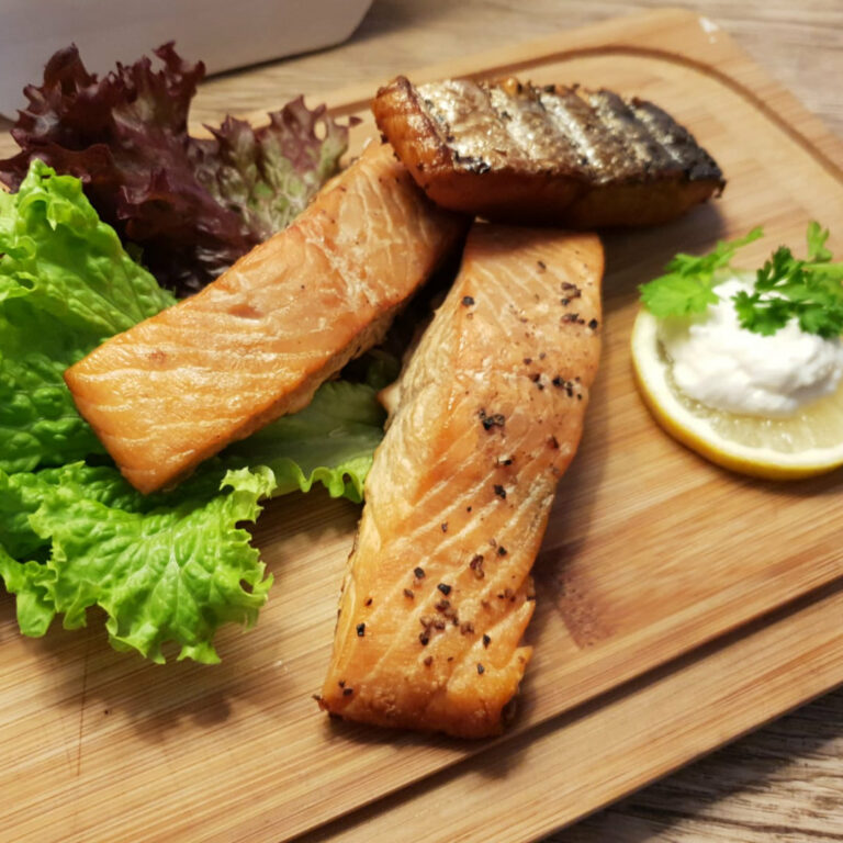 Frischer Lachs auf Holzbrett mit Salat und Zitronenscheibe