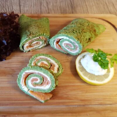 Lachsspinatrolle auf Holzbrett mit frischer Zitronenscheibe