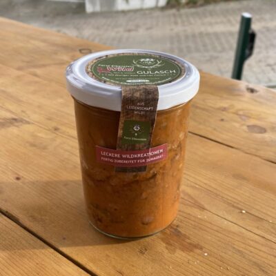 Wildgulasch im Glas auf Holzbrett