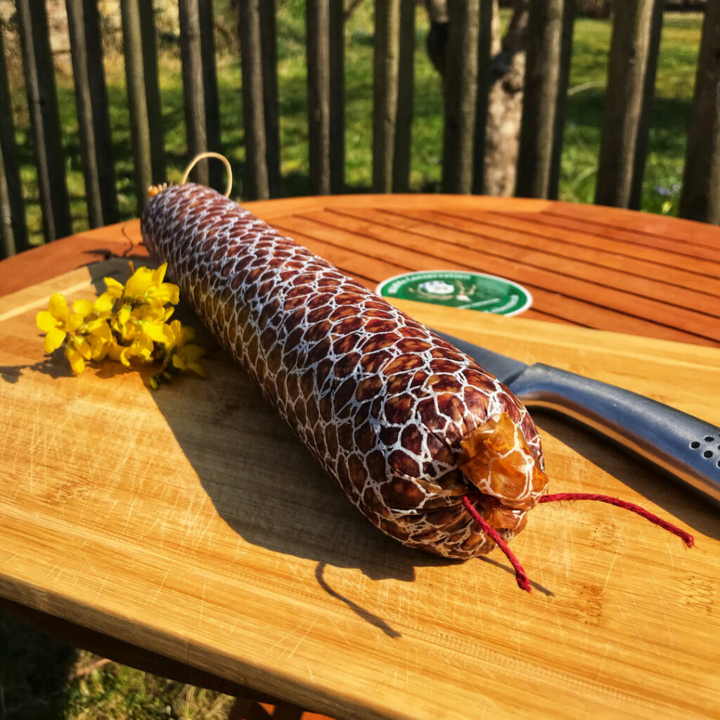 Wildsalami auf Holzbrett im Hintergrund Wald