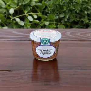 Schweinebraten im Glas auf dunklem Holzbrett