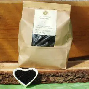 Schwarzkümmelpresskuchen in der Tüte auf Holzbrett