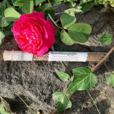 Rosenblütenpfeffer im Glas auf Rosenblättern