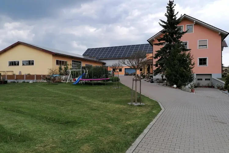 Hof mit zwei Wohngebäuden, einem Garten und einer Solaranlage auf dem Dach.