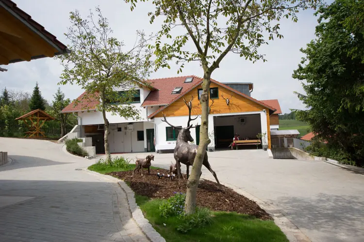 Ein modernes Haus mit Holzverkleidung und zwei Skulpturen im Garten.