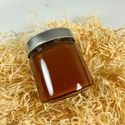 Ein Glas mit Marmelade, das auf einer Unterlage aus Holzspänen steht.