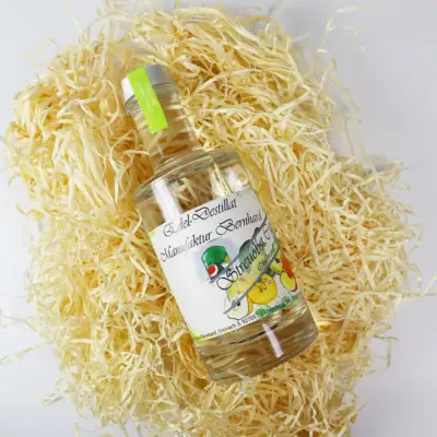 Flasche mit Edel-Destillat von der Manufaktur Bernhard auf einer Unterlage aus Stroh.