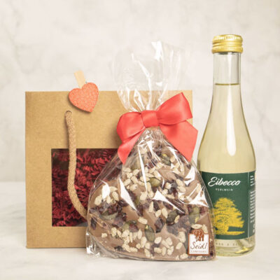 Geschenktüte mit einer Packung Süßigkeiten und einer Flasche Eibocco Getränk.