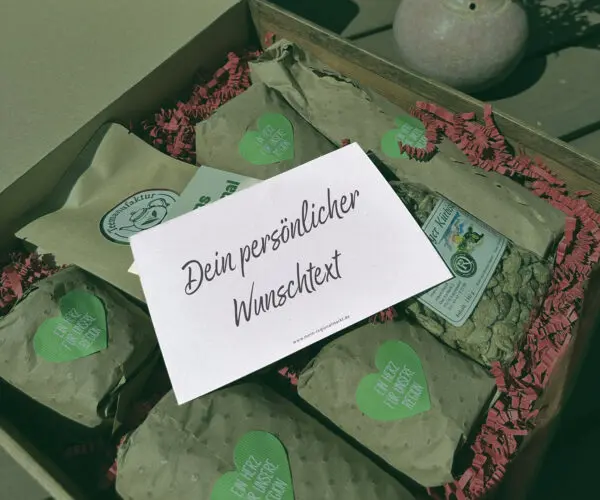 Geschenkbox mit mehreren verpackten Produkten und einer Karte mit persönlichem Wunschtext.